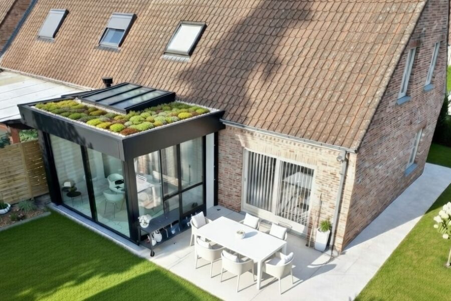 Extension moderne avec toiture végétalisée en sedum et bande de graviers autour du puits de lumière sur maison en brique